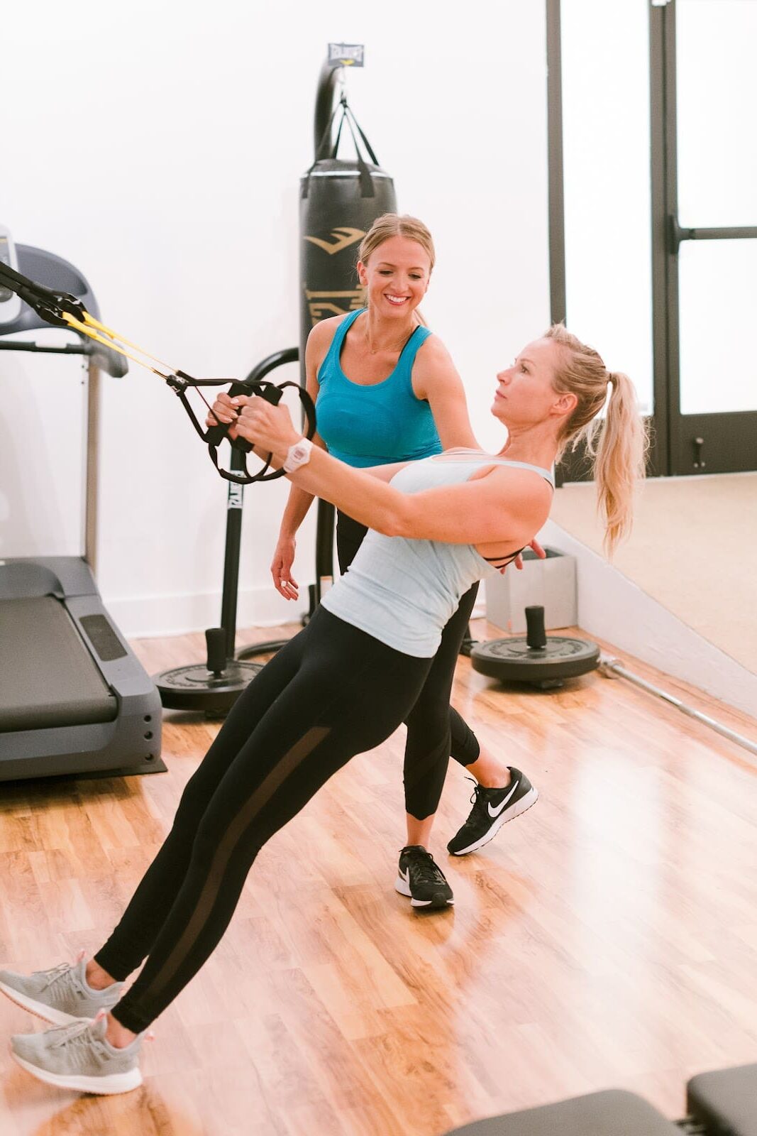 Certified female personal trainer coaching a Santa Barbara client through a suspension exercise